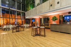 Spacious modern restaurant with glass walls, plants, and elegant decor ideal for events.