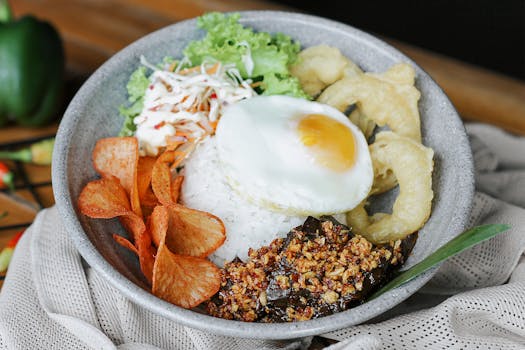 A tempting bowl of Indonesian rice topped with egg, chips, and crispy toppings.